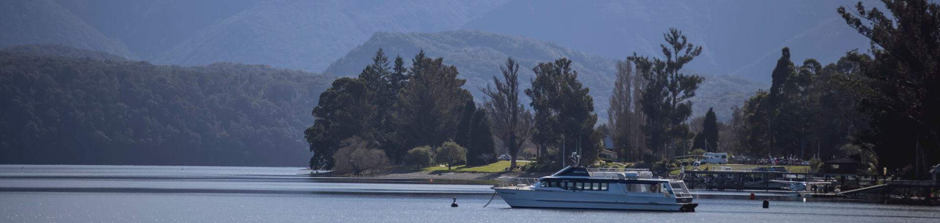 The Te Anau lakefront walkway, with the lake and Fiordland mountains in view and a boat along the shoreline.