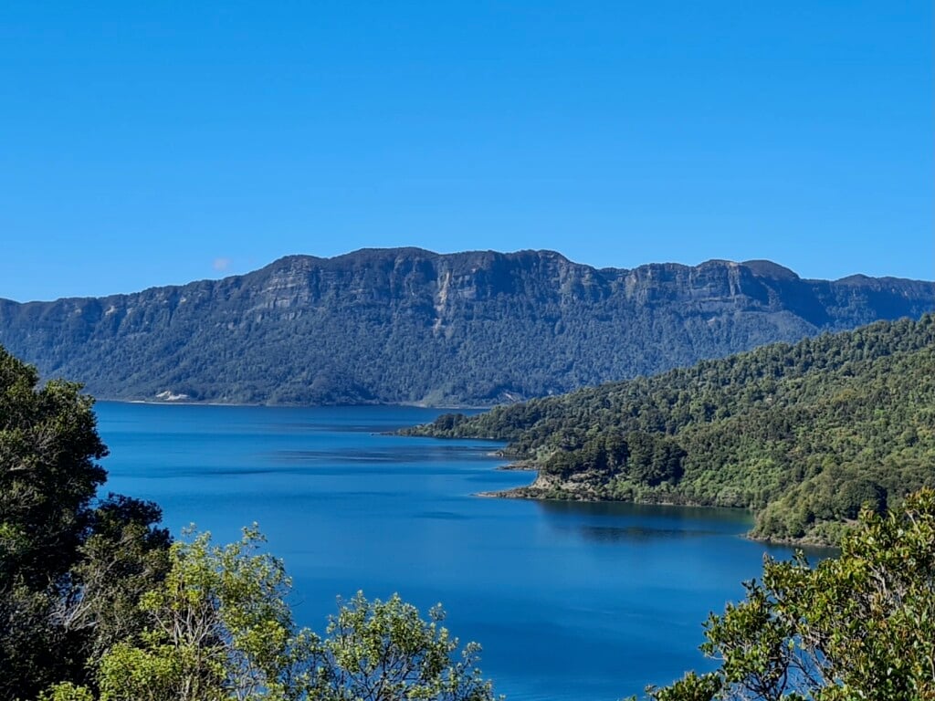 The trail offers glimpses of the expansive wilderness of forests, lakes, and volcanoes in the distance.