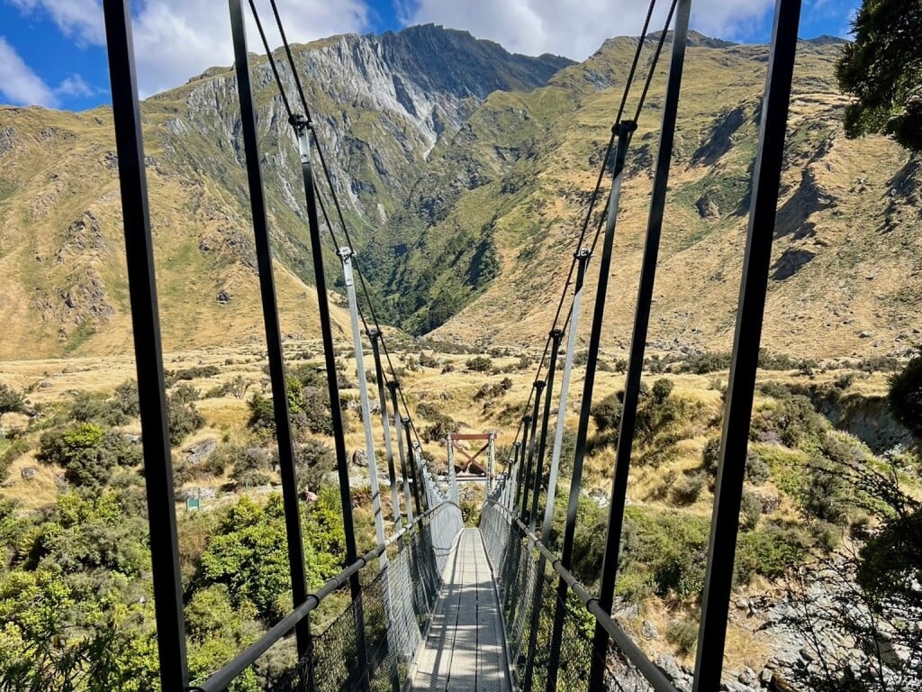 Pausing on the swingbridge to admire Mt Aspiring National Park's wild rivers and rugged peaks beyond.